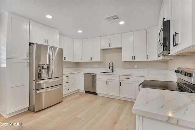 3846 W Cavalier Dr, Phoenix, AZ 85019 - kitchen featuring light wood-type flooring, light stone counters, visible vents, stainless steel appliances, and a sink