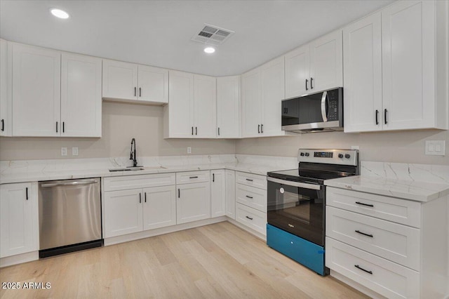 3846 W Cavalier Dr, Phoenix, AZ 85019 - kitchen featuring white cabinetry, visible vents, light stone counters, a sink, and stainless steel appliances