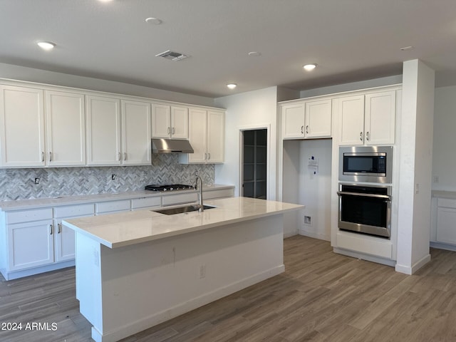 kitchen with light hardwood / wood-style flooring, white cabinetry, stainless steel appliances, and an island with sink