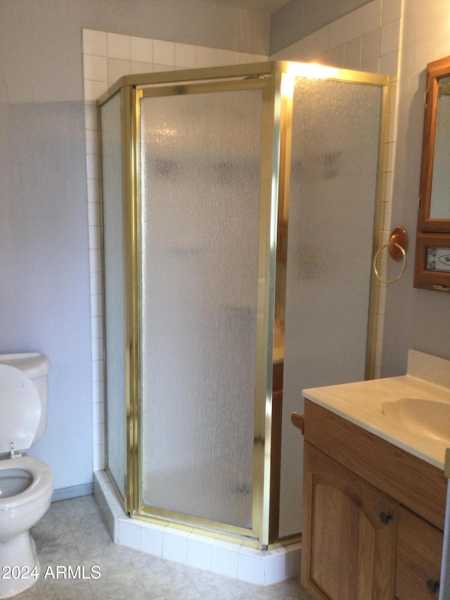 bathroom with a shower with door, toilet, tile patterned flooring, and vanity