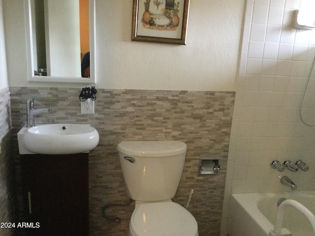 full bathroom featuring vanity, toilet, tile walls, and tiled shower / bath