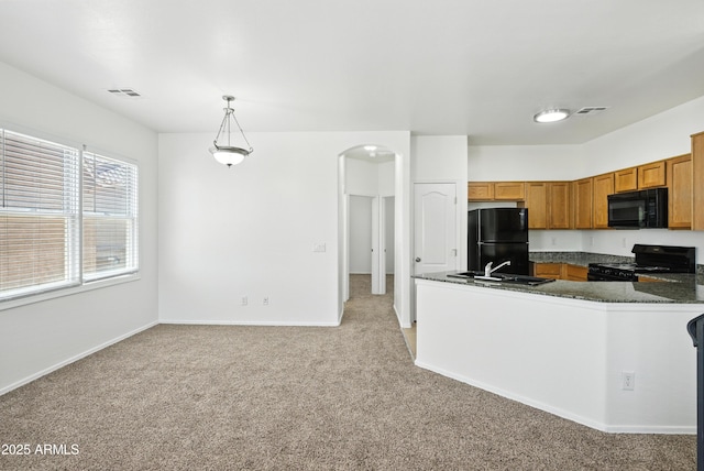 2109 E Fraktur Rd, Phoenix, AZ 85040 - kitchen featuring black appliances, light colored carpet, brown cabinetry, decorative light fixtures, and arched walkways