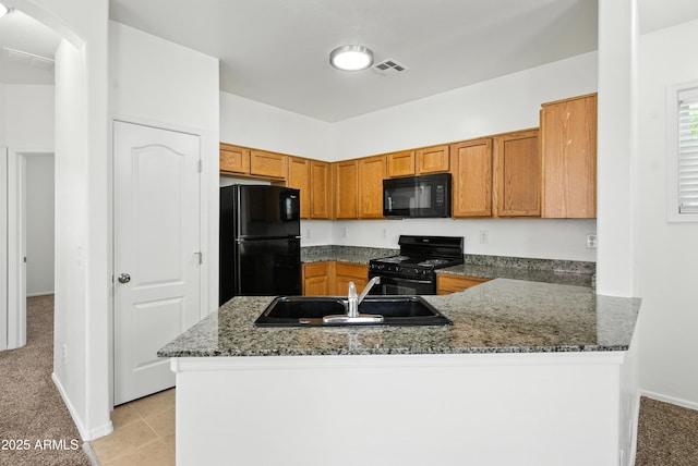 2109 E Fraktur Rd, Phoenix, AZ 85040 - kitchen featuring black appliances, brown cabinets, a peninsula, light colored carpet, and dark stone counters