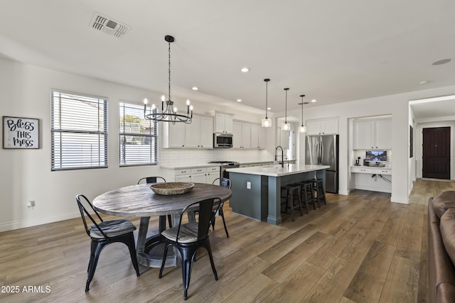 dining area featuring baseboards, visible vents, wood finished floors, a notable chandelier, and recessed lighting