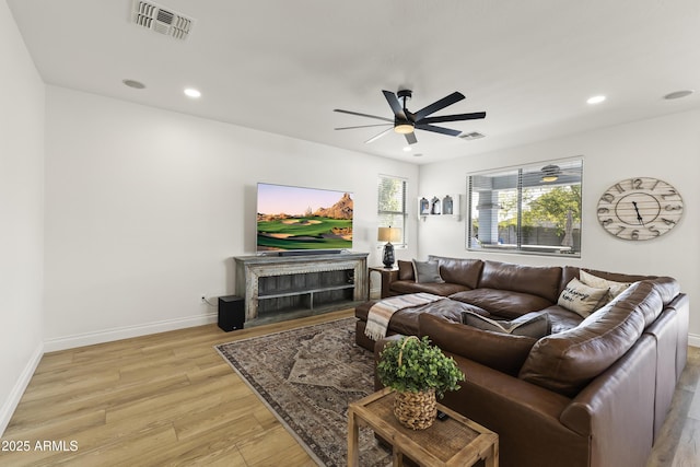 living room with light wood-style flooring, visible vents, baseboards, and recessed lighting