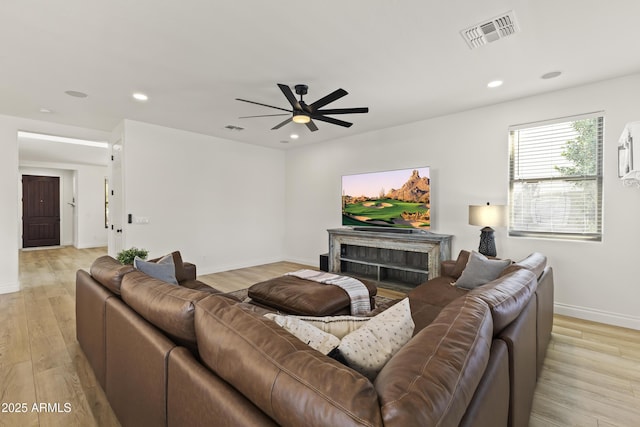 living room with light wood-style flooring, a fireplace, visible vents, and recessed lighting