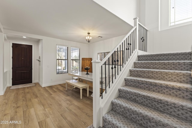 foyer with light wood-style floors, baseboards, stairway, and a chandelier