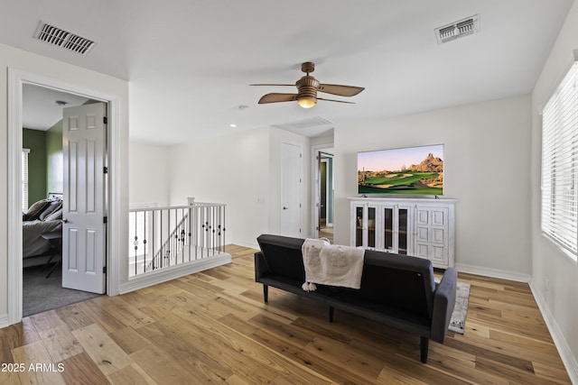 sitting room with wood finished floors, an upstairs landing, visible vents, and baseboards