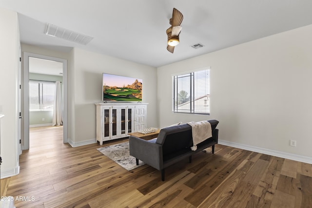 living area with hardwood / wood-style flooring, visible vents, and baseboards