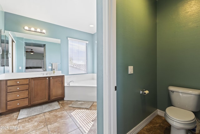 bathroom featuring toilet, ceiling fan, vanity, baseboards, and a bath