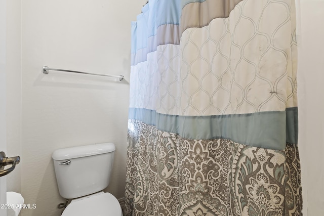 bathroom featuring toilet and curtained shower