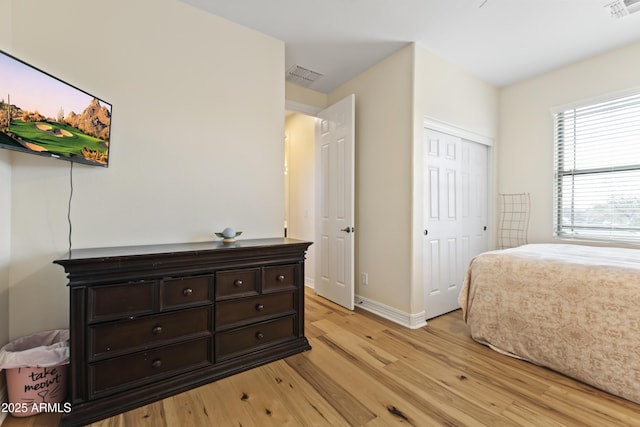 bedroom featuring light wood-style floors, baseboards, visible vents, and a closet