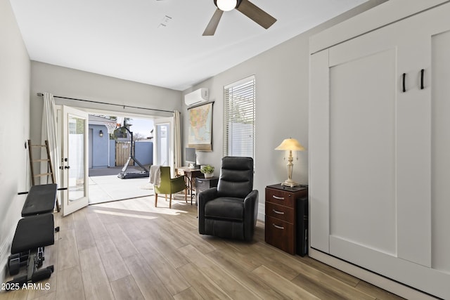 living area featuring a wall unit AC, ceiling fan, and wood finished floors