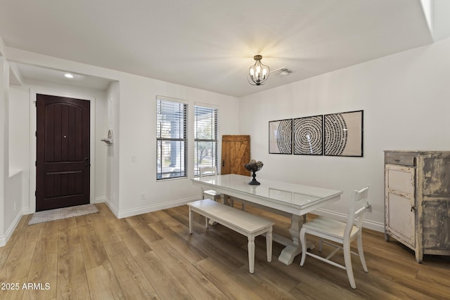 dining room with baseboards, visible vents, light wood-style flooring, and an inviting chandelier