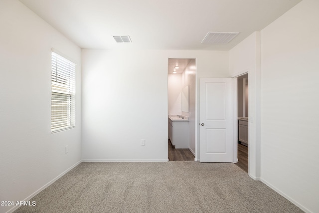 unfurnished bedroom featuring carpet flooring, connected bathroom, and sink