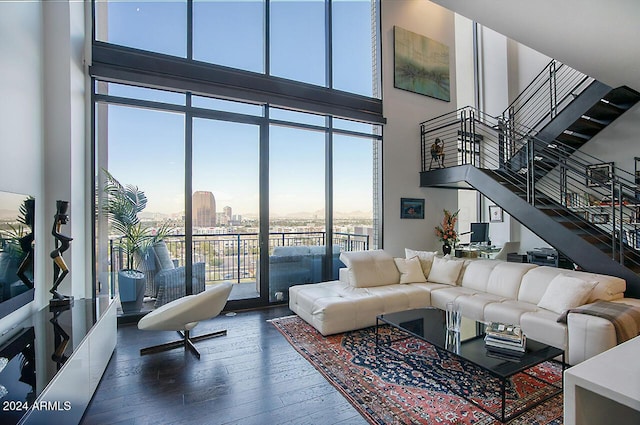 living room featuring dark wood-type flooring, a healthy amount of sunlight, and a high ceiling