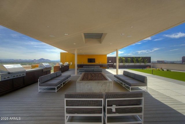 wooden deck featuring grilling area, a mountain view, and an outdoor living space with a fire pit