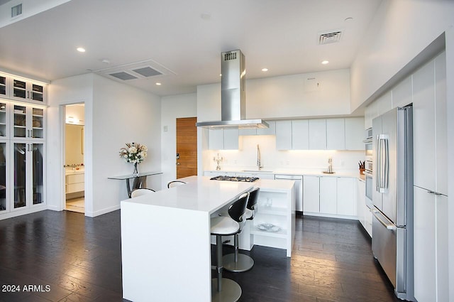 kitchen with a kitchen island, a breakfast bar area, island range hood, white cabinets, and appliances with stainless steel finishes