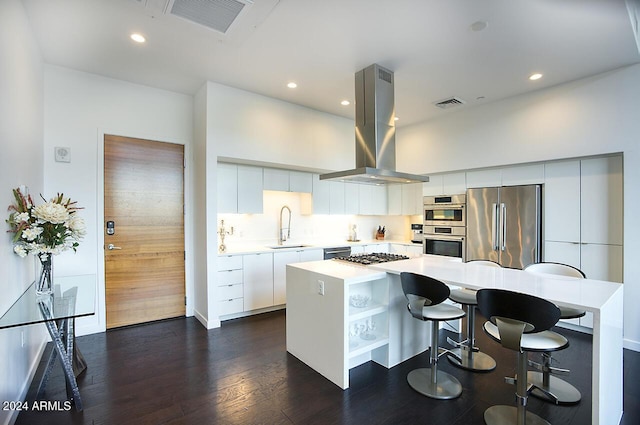 kitchen with island exhaust hood, stainless steel appliances, sink, a center island, and white cabinetry