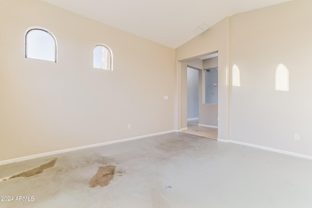 unfurnished room with vaulted ceiling and concrete flooring