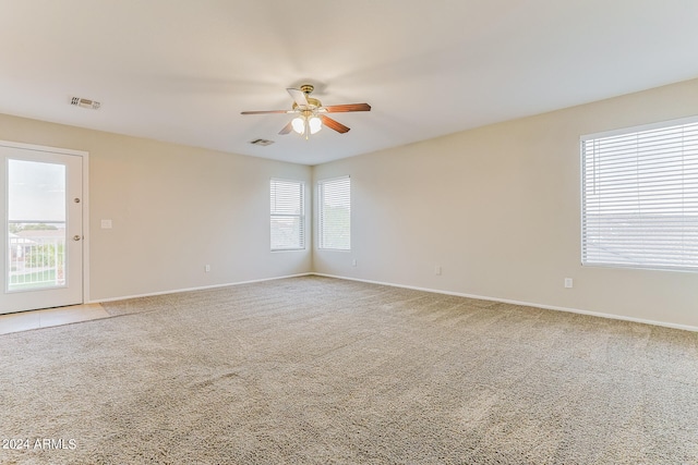 carpeted empty room with ceiling fan and plenty of natural light