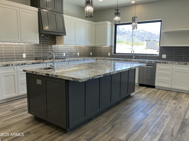 4079 E Roosevelt St, Apache Junction, AZ 85119 - kitchen featuring appliances with stainless steel finishes, an island with sink, light stone countertops, light wood-style flooring, and white cabinetry