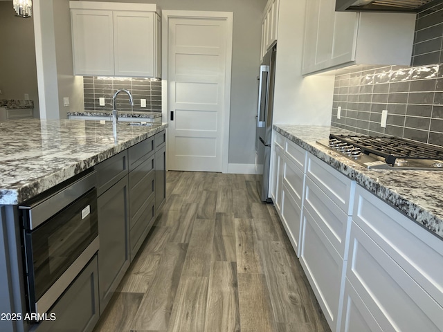 4079 E Roosevelt St, Apache Junction, AZ 85119 - kitchen with stainless steel appliances, wood finished floors, backsplash, extractor fan, and light stone counters