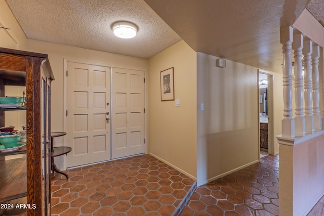 foyer with a textured ceiling and dark tile patterned flooring