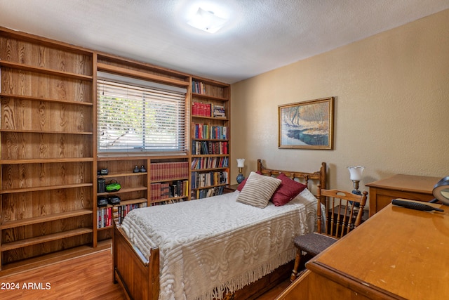 bedroom featuring a textured ceiling and light hardwood / wood-style flooring