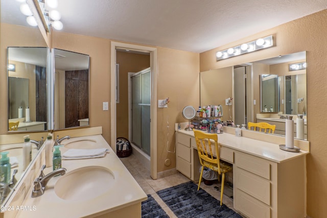 bathroom featuring tile patterned floors, a shower with door, vanity, and a textured ceiling