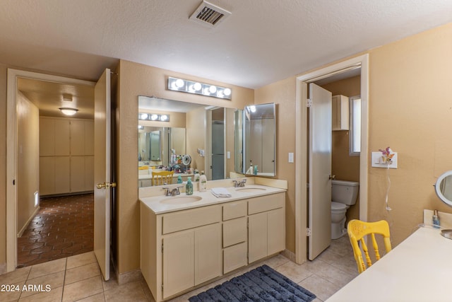 bathroom with vanity, toilet, a textured ceiling, and tile patterned floors