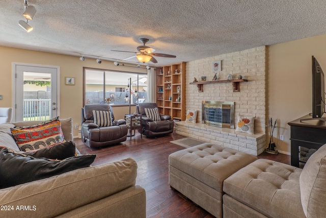 living room with a textured ceiling, a fireplace, ceiling fan, and dark hardwood / wood-style flooring