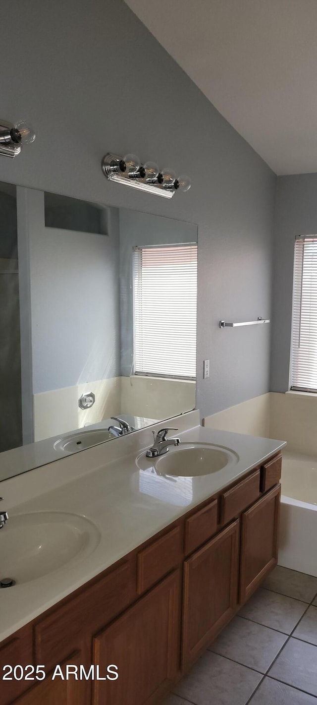 bathroom with vanity, vaulted ceiling, a washtub, and tile patterned floors