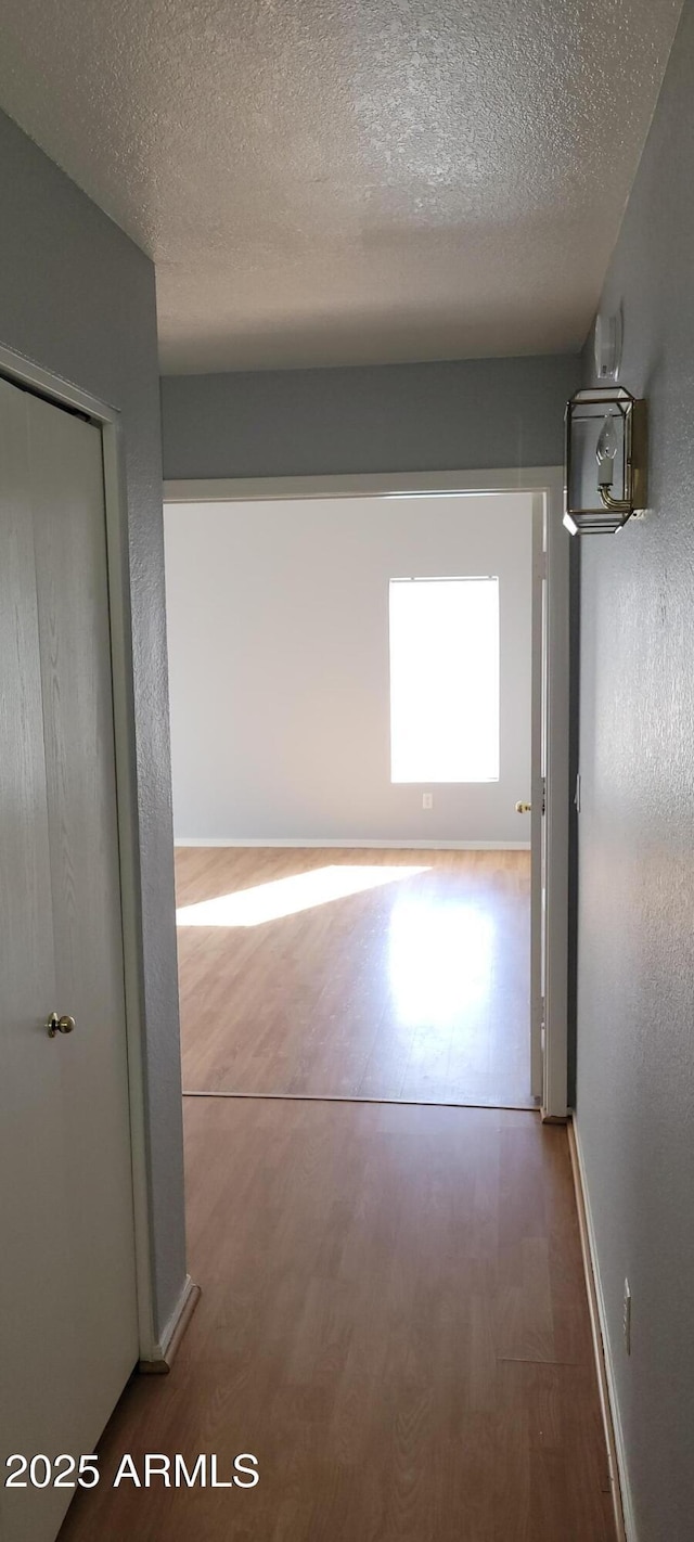 corridor with hardwood / wood-style floors and a textured ceiling