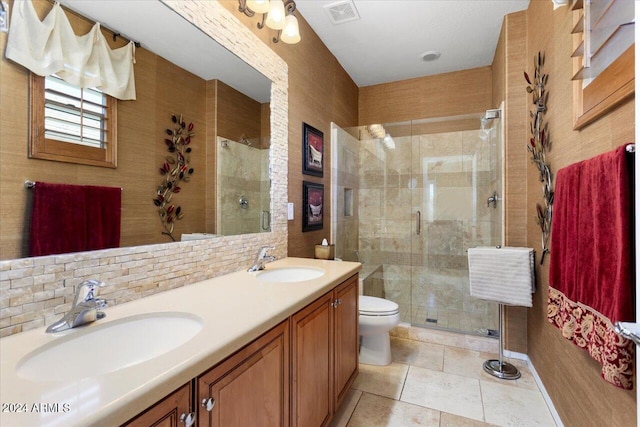 bathroom featuring tile patterned flooring, vanity, a shower with shower door, toilet, and decorative backsplash