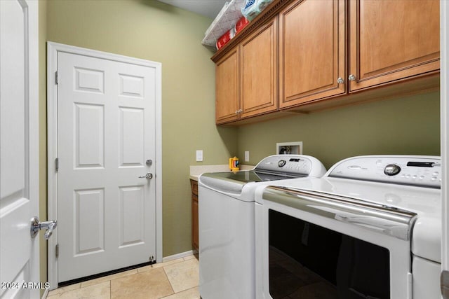 clothes washing area featuring cabinets, independent washer and dryer, and light tile patterned floors