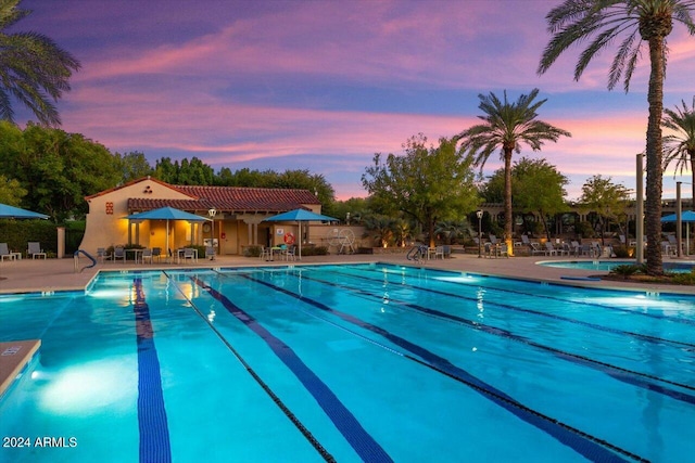 pool at dusk with a patio area