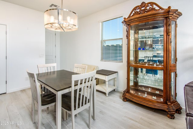 dining room featuring light wood-type flooring and an inviting chandelier