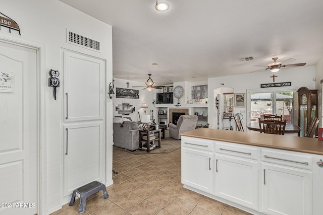 kitchen featuring white cabinets, ceiling fan, and light tile flooring