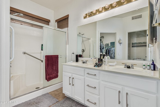 bathroom featuring a shower with door, large vanity, tile floors, and dual sinks