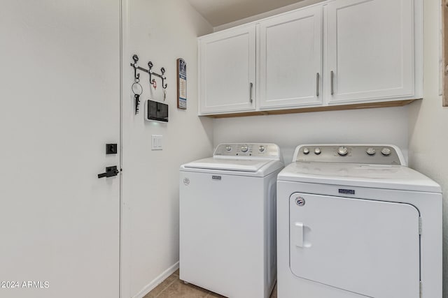 washroom with cabinets, separate washer and dryer, and light tile floors