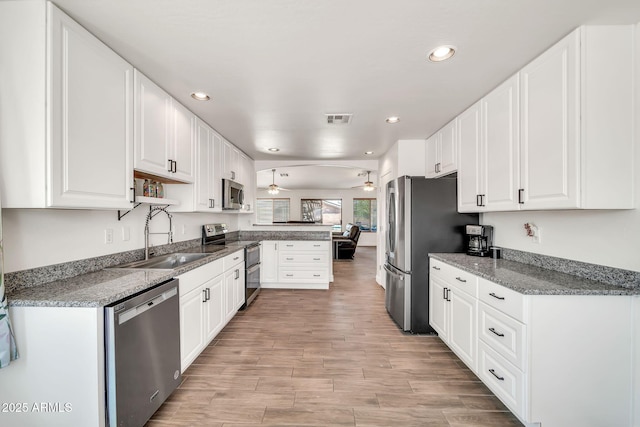15019 W Banff Ln, Surprise, AZ 85379 - kitchen with stainless steel appliances, a peninsula, ceiling fan, white cabinetry, and recessed lighting