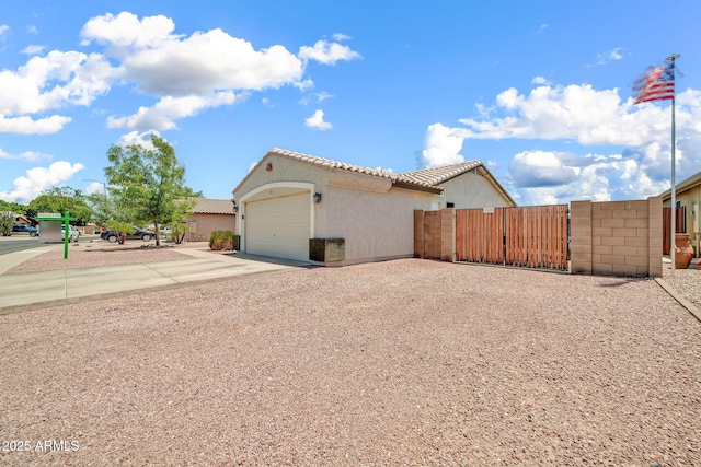15019 W Banff Ln, Surprise, AZ 85379 - view of side of property featuring driveway, stucco siding, a tile roof, an attached garage, and a gate