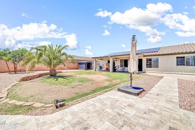 15019 W Banff Ln, Surprise, AZ 85379 - rear view of property with a patio, a storage unit, solar panels, stucco siding, and a tile roof