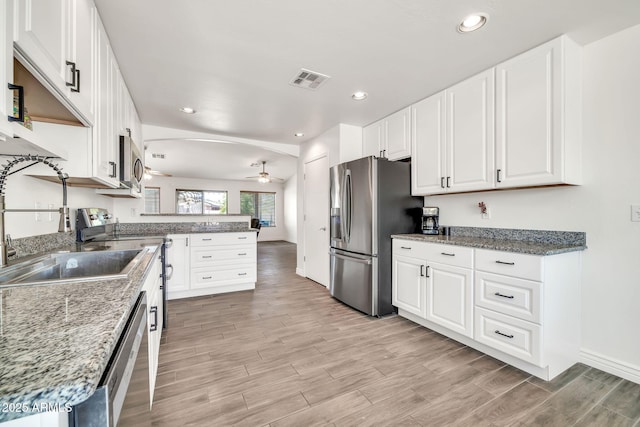 15019 W Banff Ln, Surprise, AZ 85379 - kitchen with stainless steel appliances, a ceiling fan, a peninsula, light wood-style floors, and white cabinetry