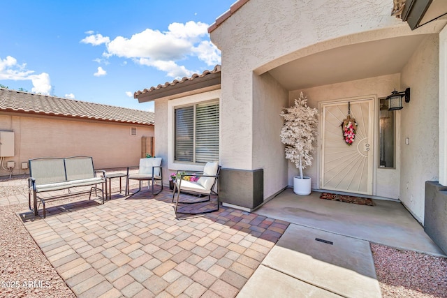 15019 W Banff Ln, Surprise, AZ 85379 - view of exterior entry featuring stucco siding, a patio area, an outdoor hangout area, and a tiled roof