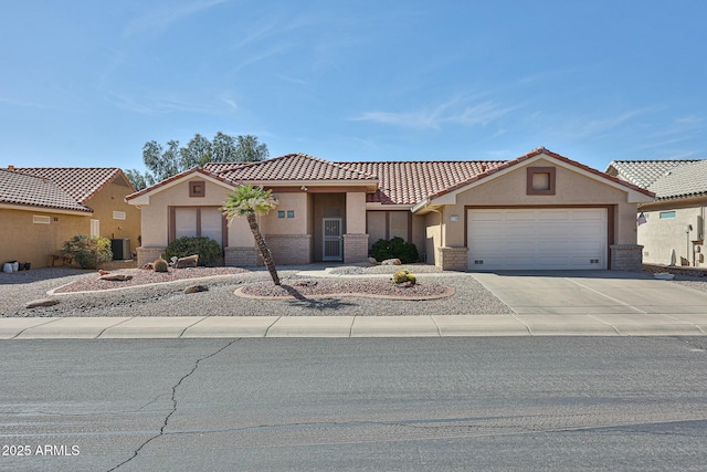 mediterranean / spanish-style home featuring an attached garage, cooling unit, brick siding, concrete driveway, and stucco siding