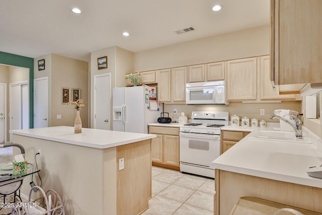 kitchen with white appliances, visible vents, a kitchen island, light brown cabinetry, and a sink