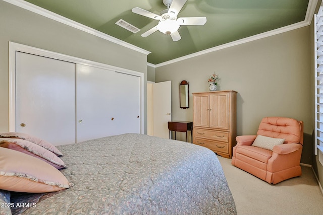 carpeted bedroom with visible vents, ornamental molding, ceiling fan, and a closet