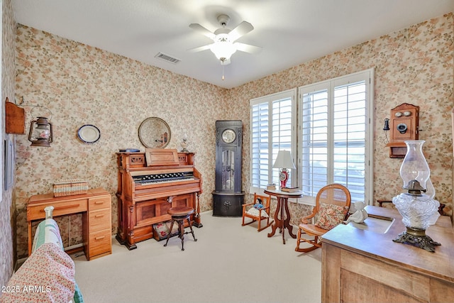 carpeted office with visible vents, ceiling fan, and wallpapered walls